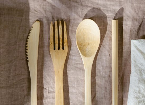 Minimalist wooden cutlery set displayed on a brown textured cloth, perfect for eco-friendly dining concepts.