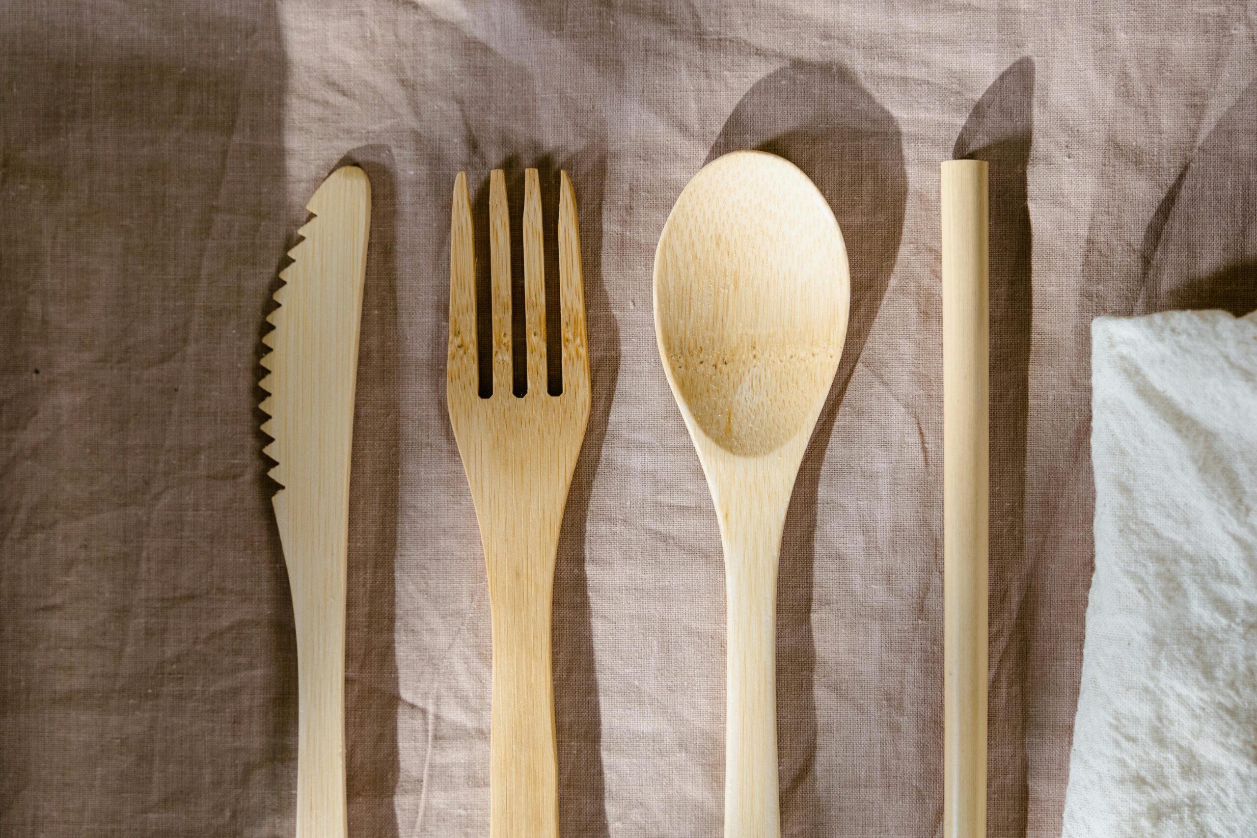 Minimalist wooden cutlery set displayed on a brown textured cloth, perfect for eco-friendly dining concepts.